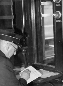 222813 Afbeelding van een conducteur (hoofdconducteur) van de N.S. tijdens het opmaken van een treinrapport in een trein.